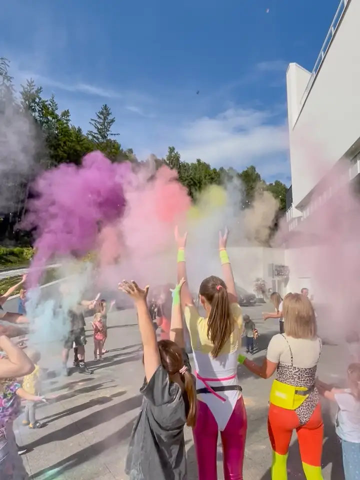 Eksplozja kolorowych proszków Holi nad głowami uczestników przed hotelem w lesie